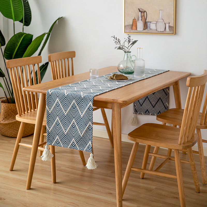 Woven table runner with geometric herringbone diamond pattern and decorative tassels