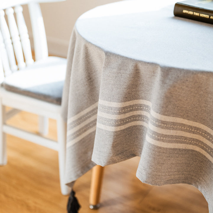 Rectangular tablecloth made of cotton-linen blend with subtle striped border and decorative tassels