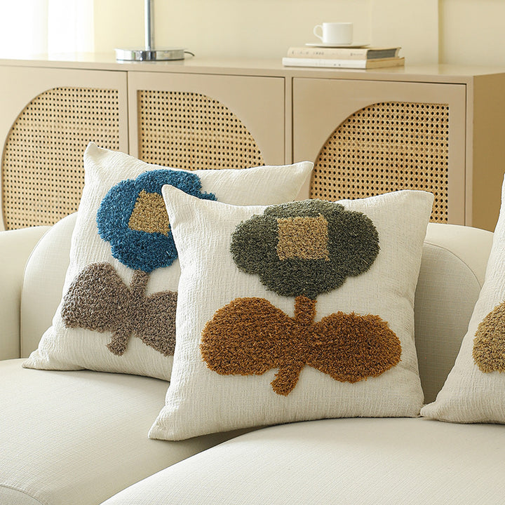 Square decorative pillow with hand-tufted floral appliqué and textured linen look
