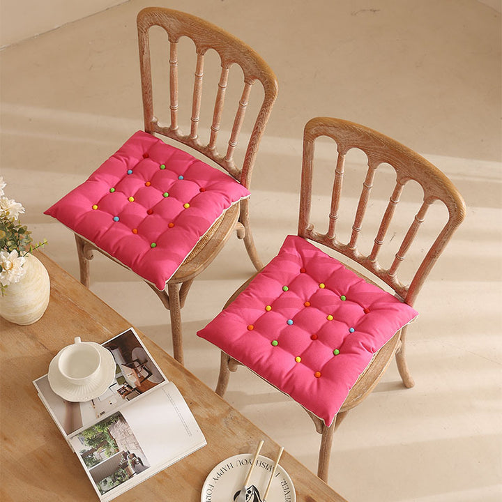 Padded quilted seat cushion with colorful button applications and non-slip underside
