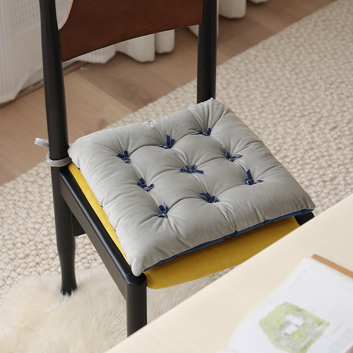 Padded square seat cushion with tufting and attachment ribbons