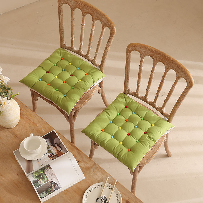 Padded quilted seat cushion with colorful button applications and non-slip underside