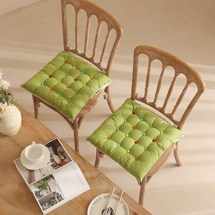 Padded quilted seat cushion with colorful button applications and non-slip underside