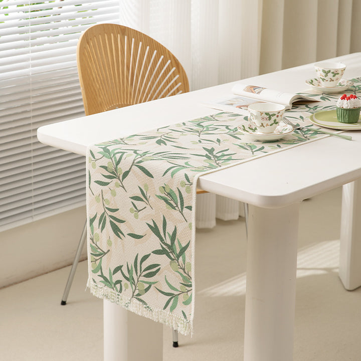 Woven botanical table runner with olive branch motif and fringed edge