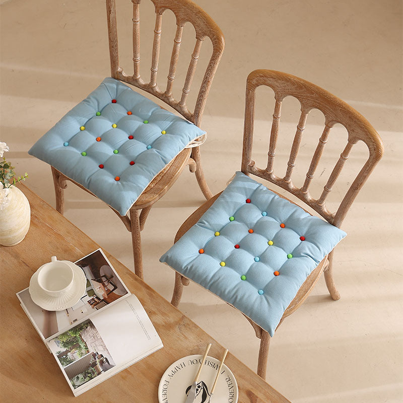 Padded quilted seat cushion with colorful button applications and non-slip underside