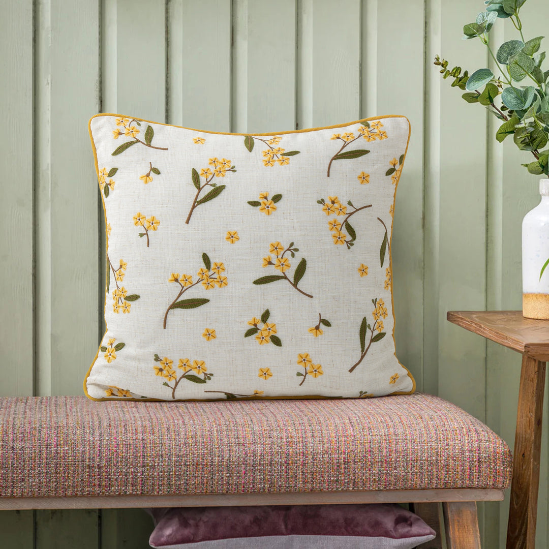 Decorative embroidered cushion cover made of linen blend with floral yellow flower appliqué and piping