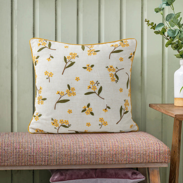 Decorative embroidered cushion cover made of linen blend with floral yellow flower appliqué and piping