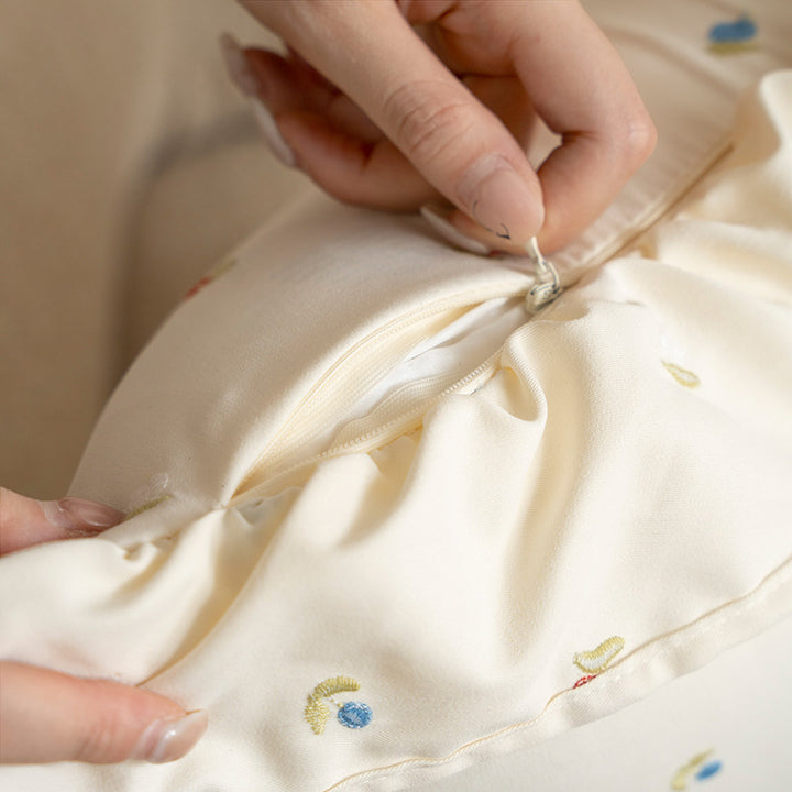 Decorative cushion with ruffles and embroidered flower pattern