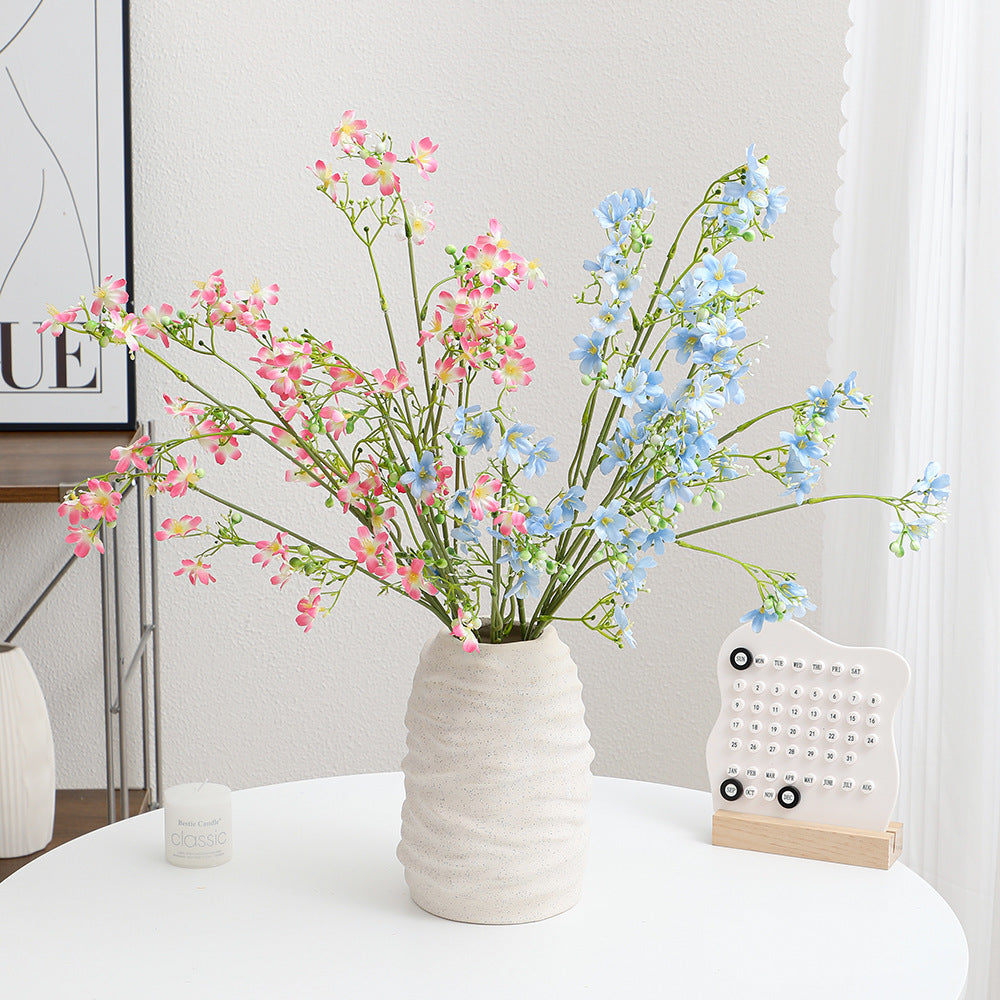 Artificial flower branch with delicate blue flowers and green berries