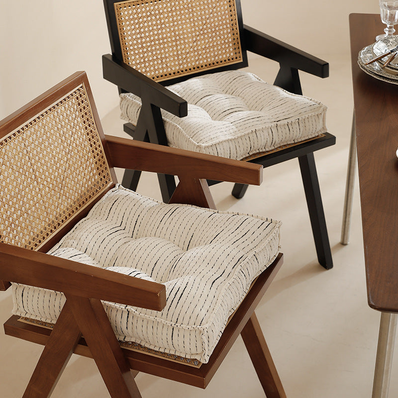 Filled floor cushion with quilted seat surface, carrying handle and fine stripe woven pattern