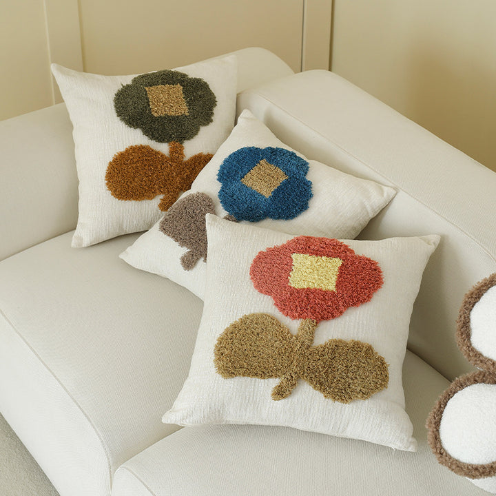 Square decorative pillow with hand-tufted floral appliqué and textured linen look
