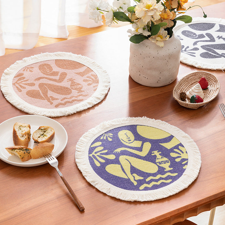 Round woven placemat with fringes and abstract figure motif