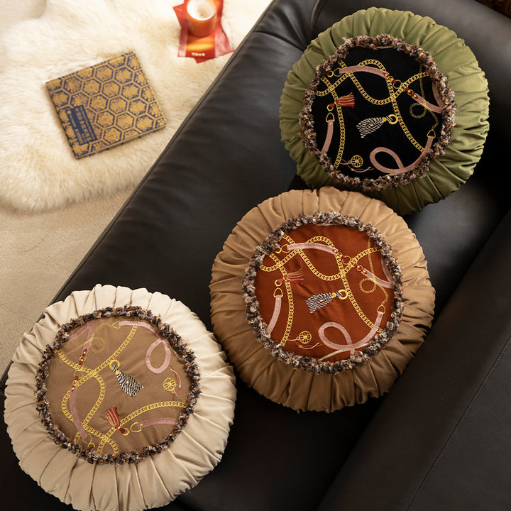 Round decorative pillow with pleated edge, fringe trim, and chain tassel motif