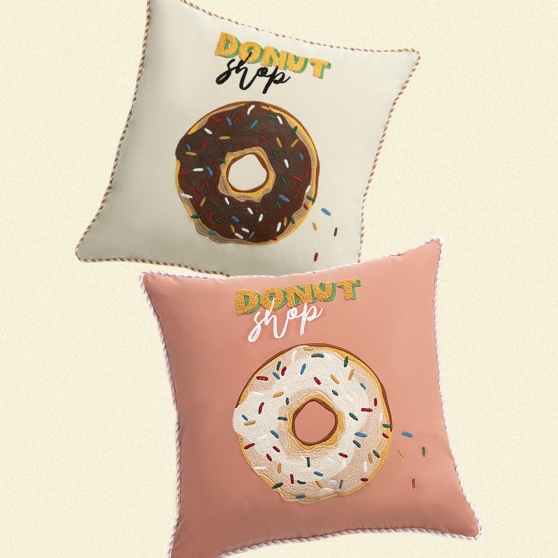 Square decorative pillow cover with hand-embroidered donut appliqué and piping