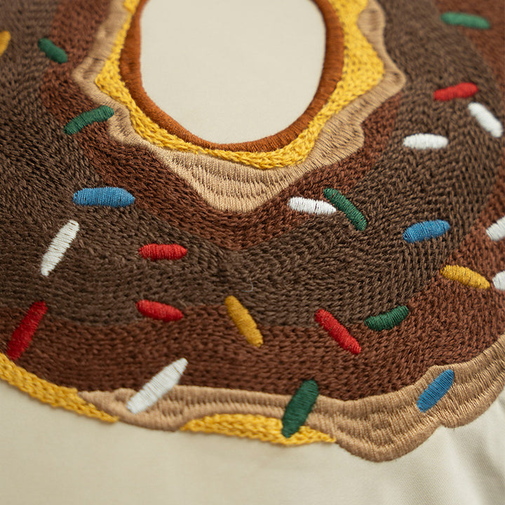 Square decorative pillow cover with hand-embroidered donut appliqué and piping