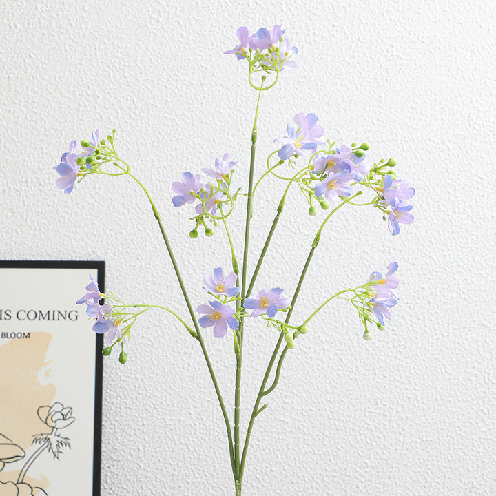 Artificial flower branch with delicate blue flowers and green berries