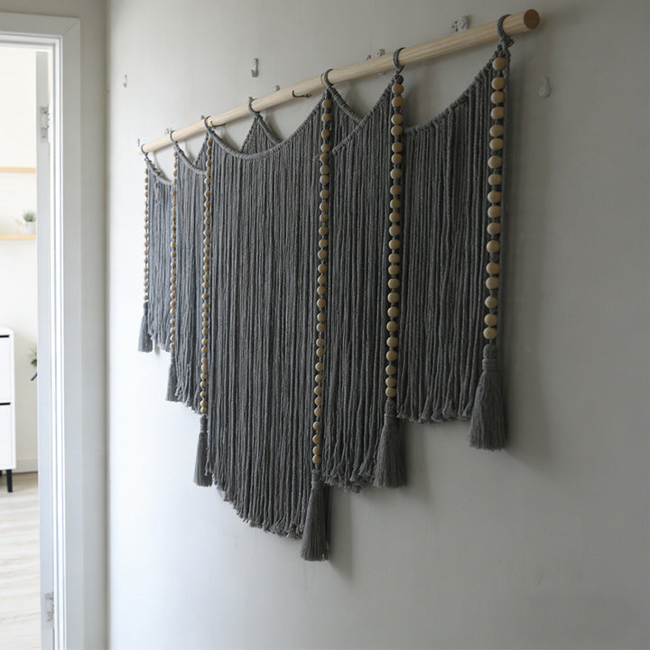 Macramé wall hanging with intricate fringes and wooden beads