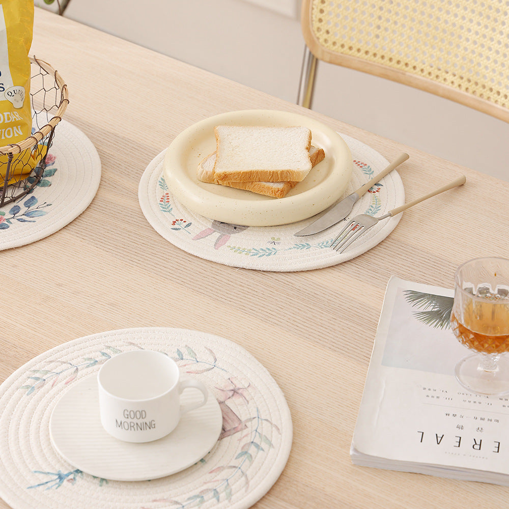 Round placemat made of woven cotton with a cute rhinoceros illustration and floral wreath