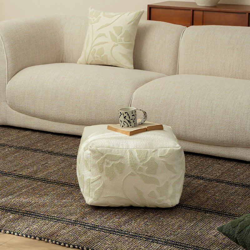 Square floor sitting pouf with textured bouclé surface and floral relief