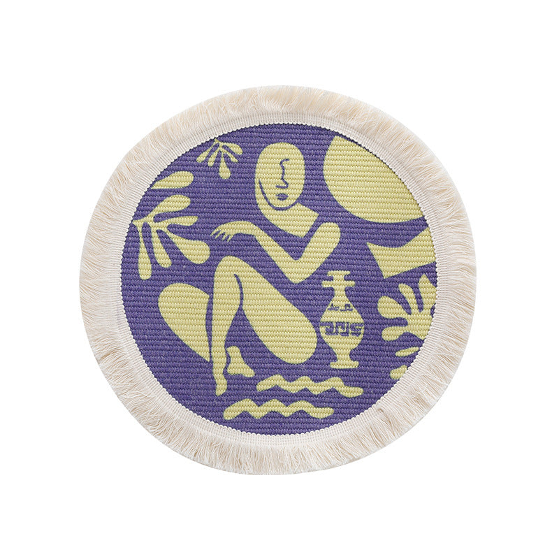 Round woven placemat with fringes and abstract figure motif