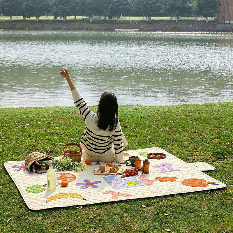 Padded outdoor picnic blanket with quilting, carrying flap and lightweight water-repellent cover