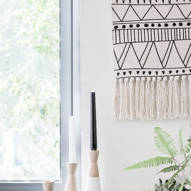 Woven wall hanging made of cotton blend with wooden rod, fringes and geometric ethnic pattern