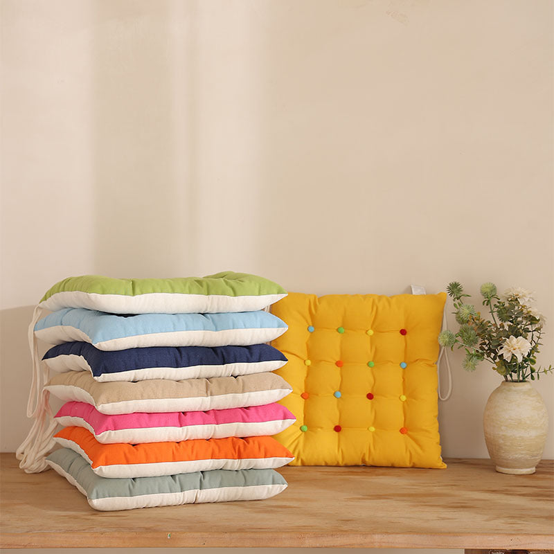 Padded quilted seat cushion with colorful button applications and non-slip underside