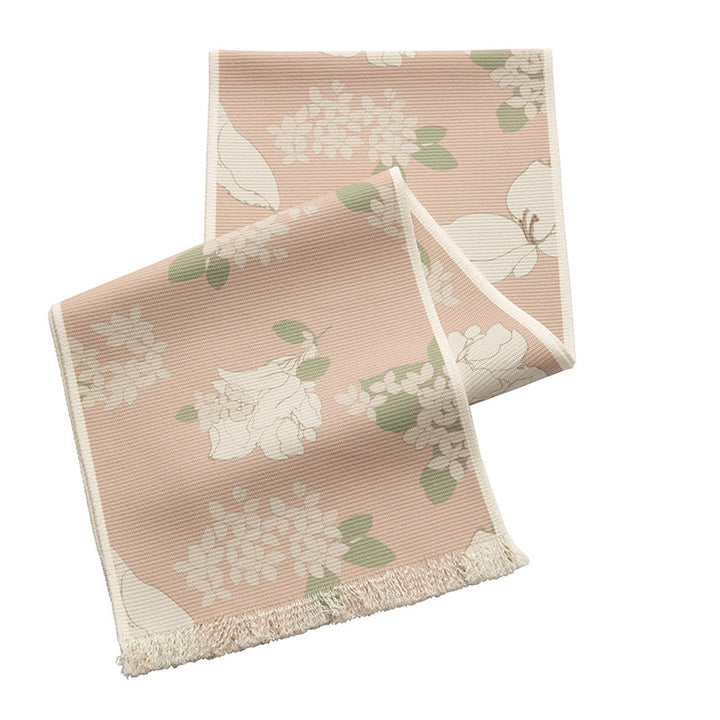 Woven table runner with floral jacquard pattern and fringed edge