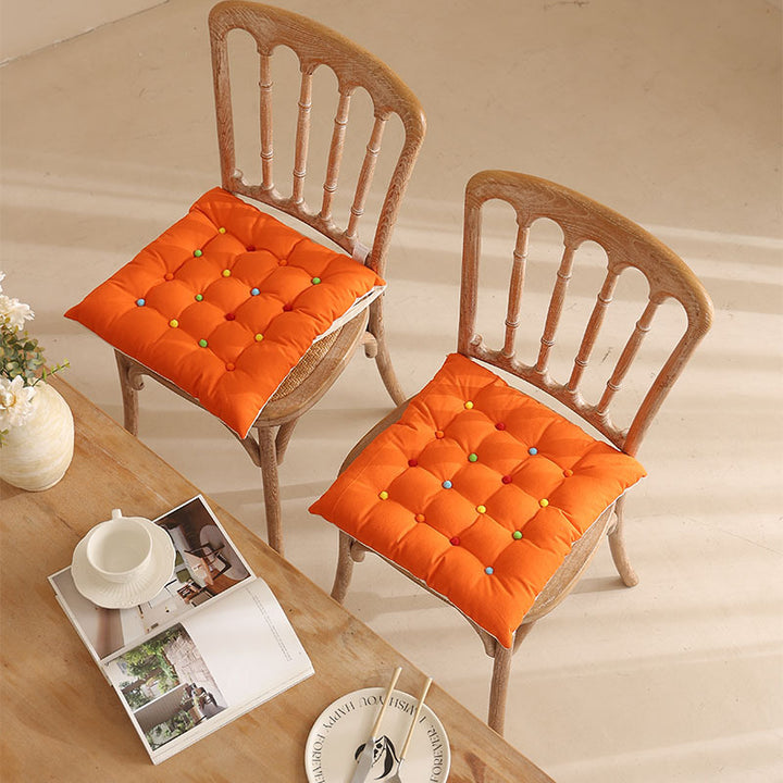Padded quilted seat cushion with colorful button applications and non-slip underside