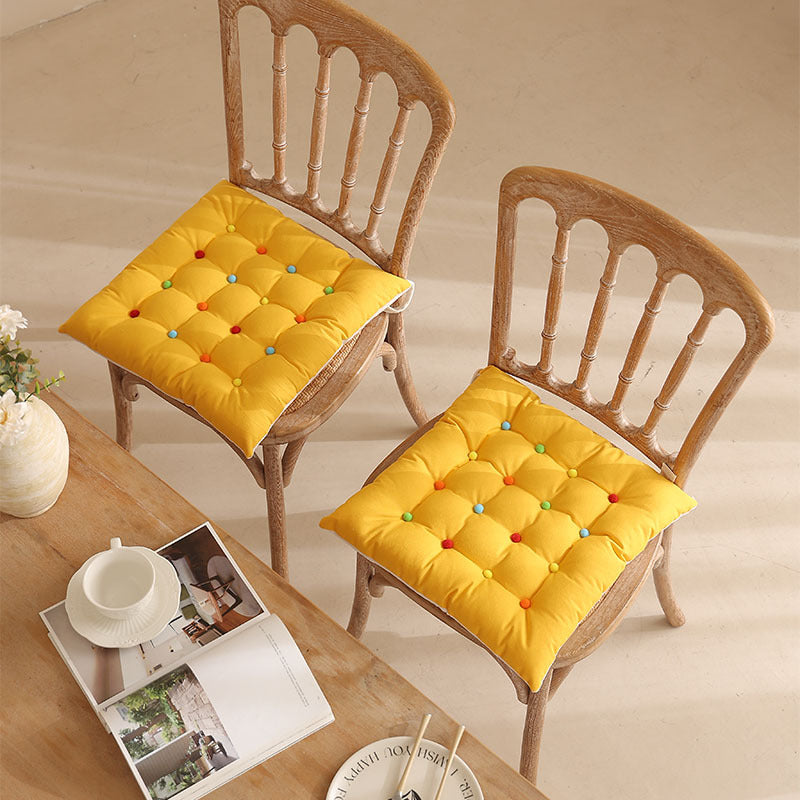 Padded quilted seat cushion with colorful button applications and non-slip underside