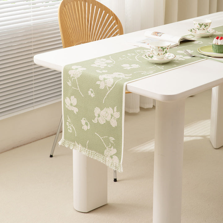 Woven table runner with floral jacquard pattern and fringed edge