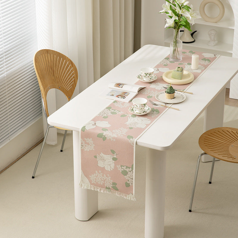 Woven table runner with floral jacquard pattern and fringed edge
