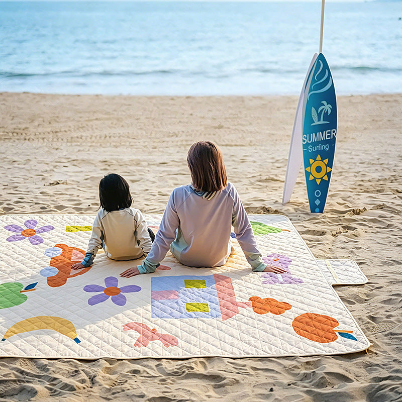 Padded outdoor picnic blanket with quilting, carrying flap and lightweight water-repellent cover