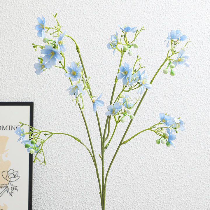 Artificial flower branch with delicate blue flowers and green berries