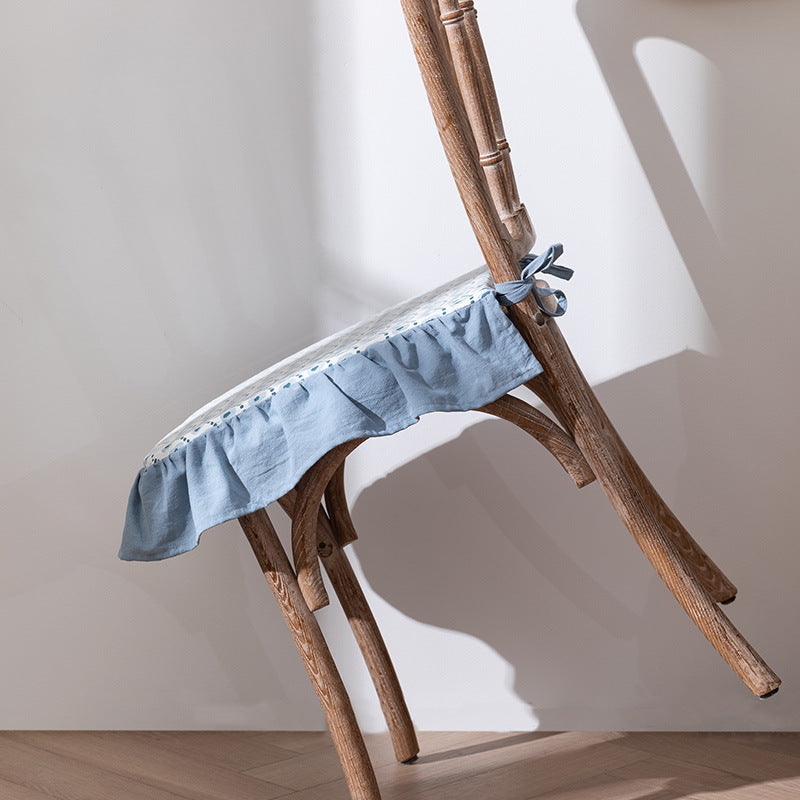 Padded chair cushion with ties, ruffled edge and embroidered hole pattern look