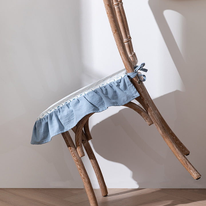Padded chair cushion with ties, ruffled edge and embroidered hole pattern look
