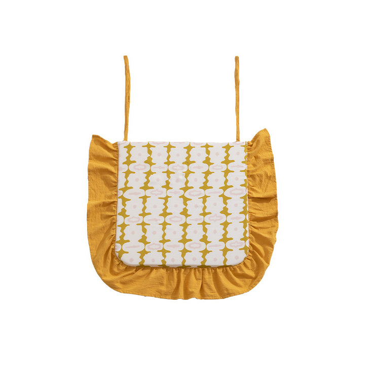Padded chair cushion with ties, ruffled edge and embroidered hole pattern look