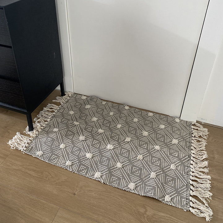 Hand-tufted bathroom mat with fringes, decorative dot-and-dash pattern and non-slip backing