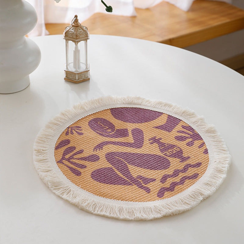 Round woven placemat with fringes and abstract figure motif