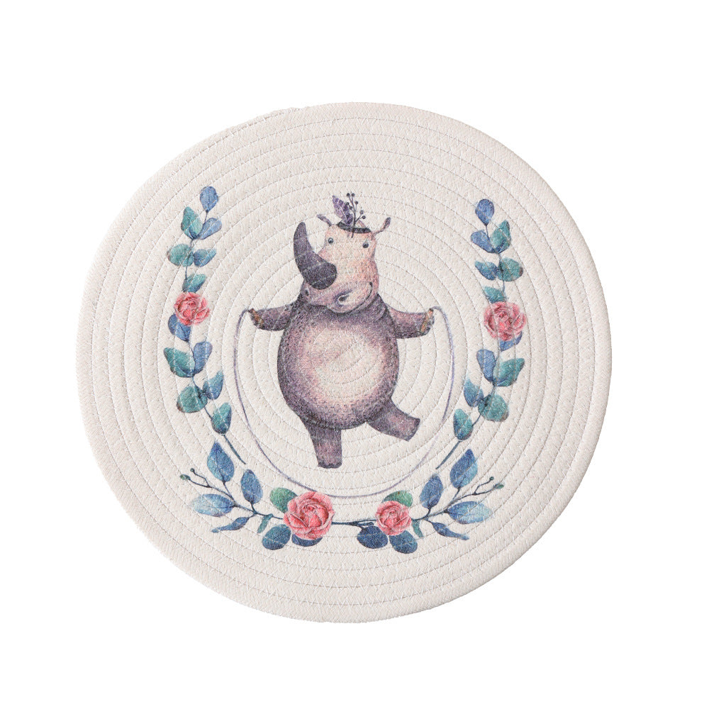 Round placemat made of woven cotton with a cute rhinoceros illustration and floral wreath
