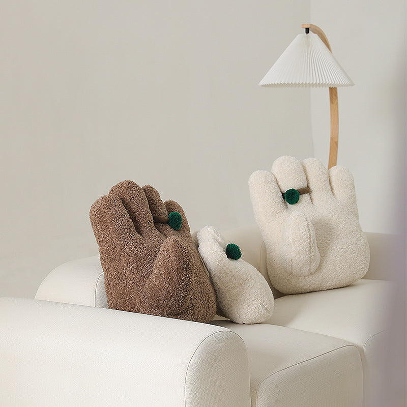 Plush decorative pillow in hand shape with pompon application