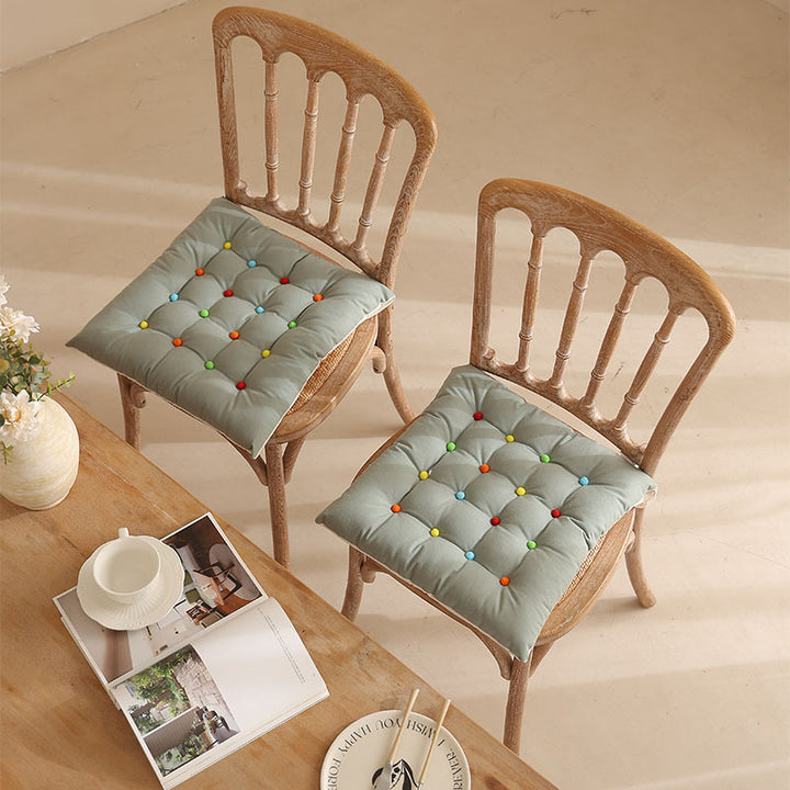 Padded quilted seat cushion with colorful button applications and non-slip underside