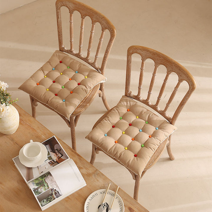 Padded quilted seat cushion with colorful button applications and non-slip underside
