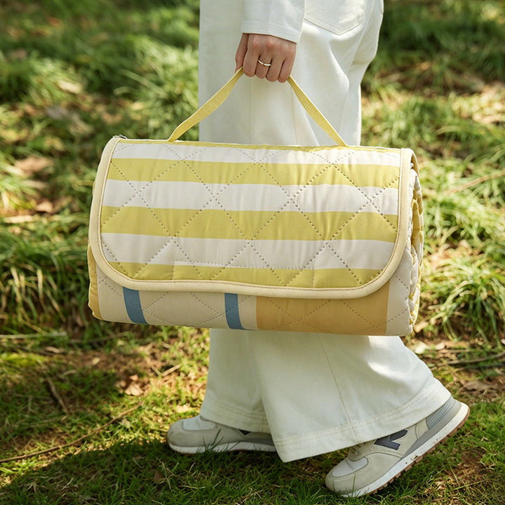 Padded outdoor picnic blanket with quilting, carrying flap and lightweight water-repellent cover