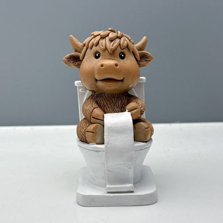 Funny decorative figure of a Highland cow on toilet