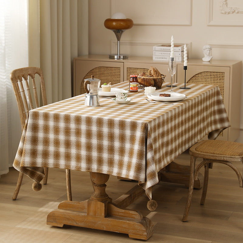 Square tablecloth made of cotton blend fabric with checkered weave pattern and pom-pom corners