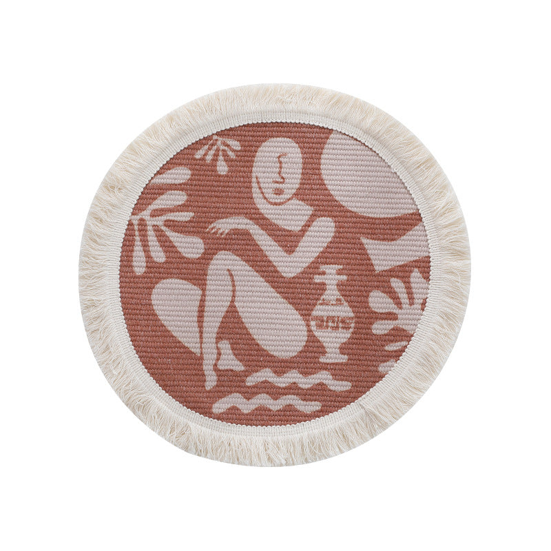Round woven placemat with fringes and abstract figure motif