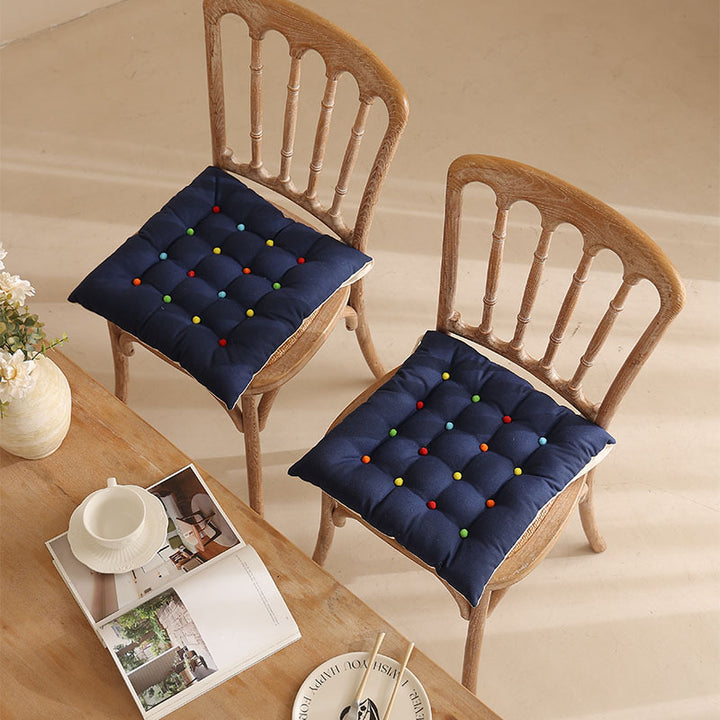 Padded quilted seat cushion with colorful button applications and non-slip underside