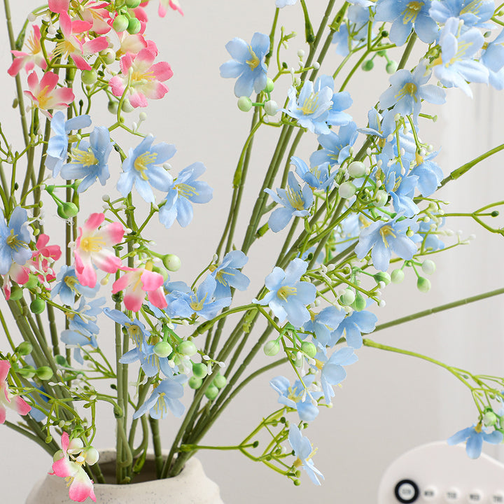 Artificial flower branch with delicate blue flowers and green berries
